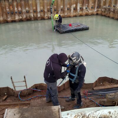 Industrietaucher vor einem abgesteckten Becken voller Wasser