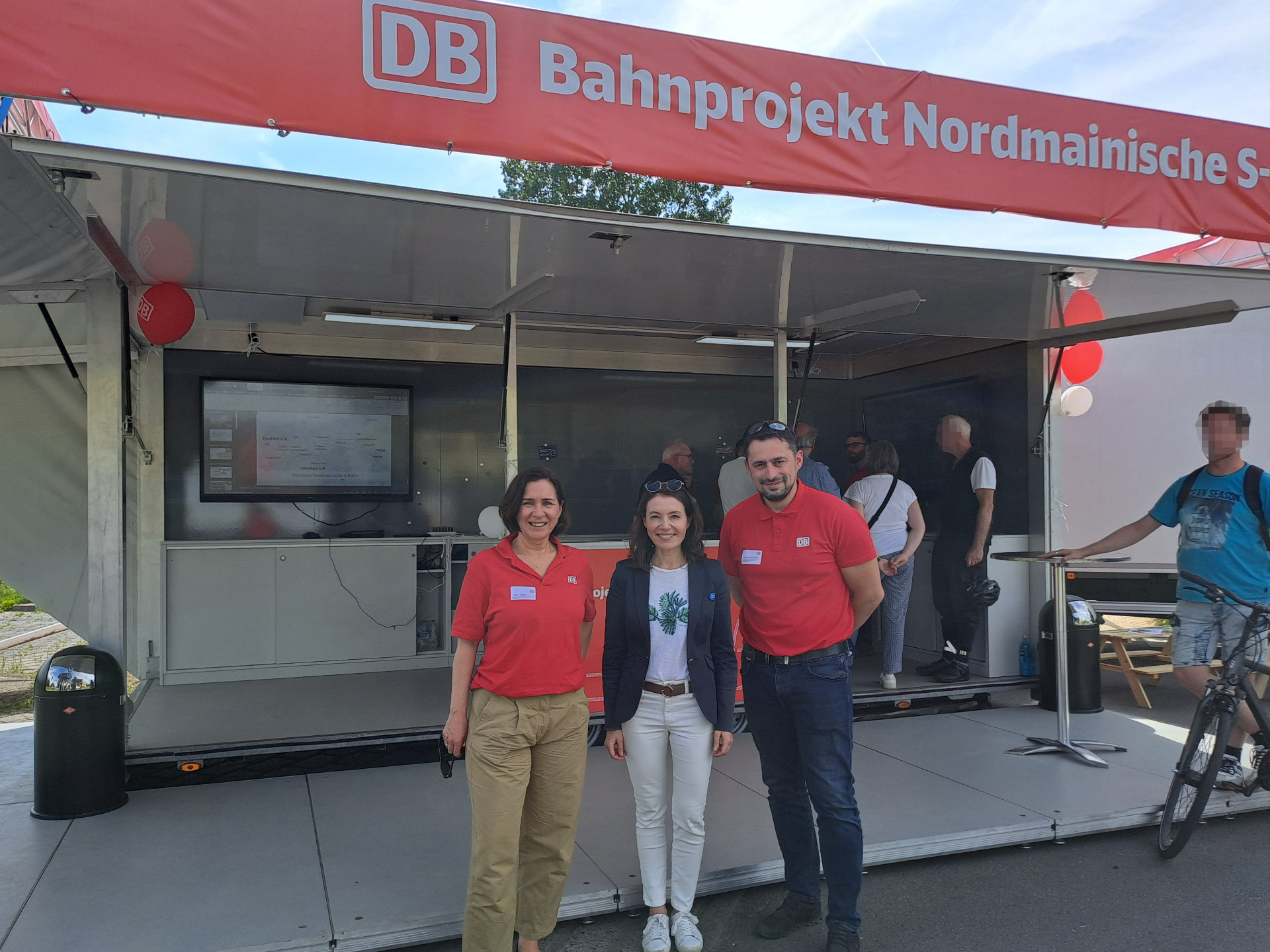 Bürgermeisterin Monika Böttcher (mit Projektleiterin Belgin Baser und Vadim Krawtschuk, Teilprojektleiter Maintal) vor dem DB Infomobil