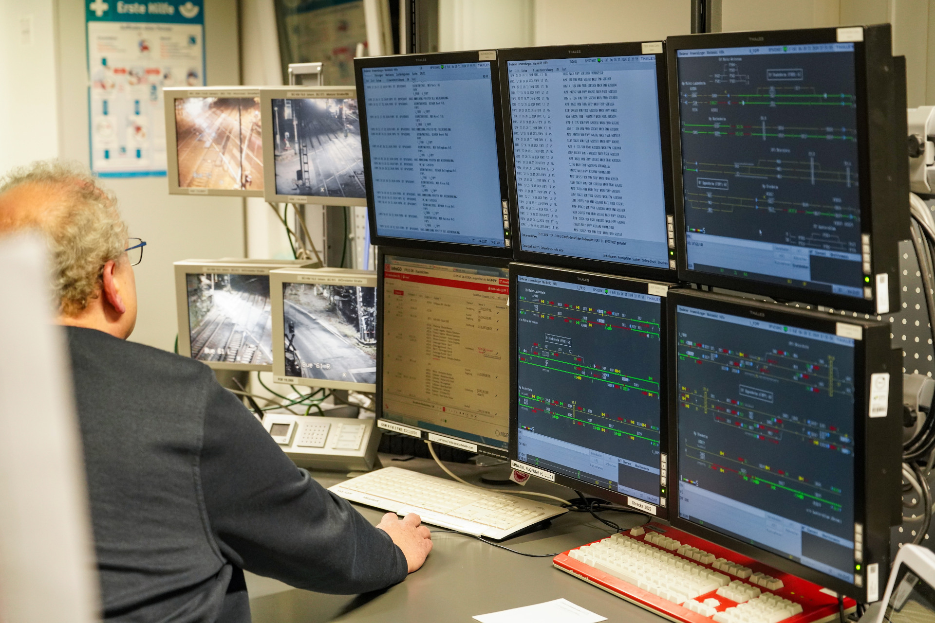 Ein Mann schaut auf sechs Computermonitore mit Daten und vier kleinere Überwachungsmonitore daneben.